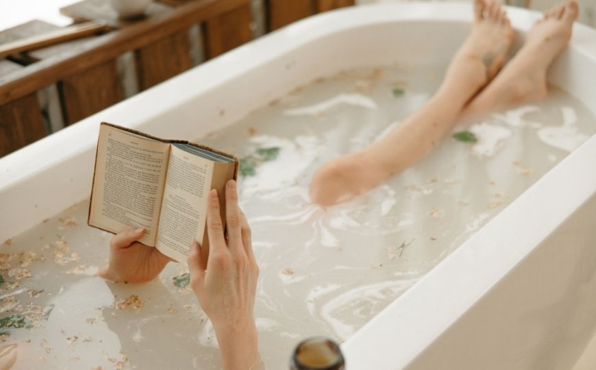 Woman taking a bath and reading a book