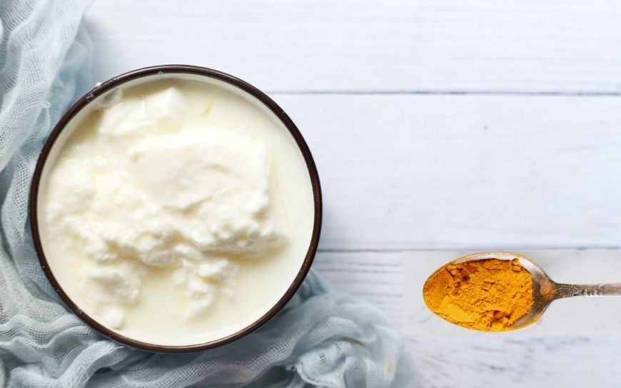 A bowl with Greek yogurt and a spoon with turmeric