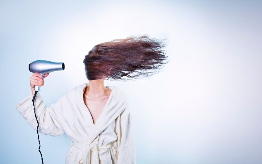 Hair oils to protect from heating Woman blow-drying her hair