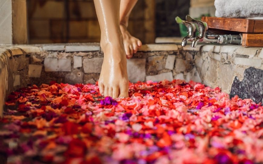 Woman entering a bath tube with flowers