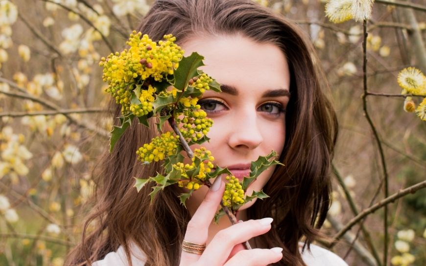 Skin Care Products you Should be Using in your 20’s Woman in her 20's holding a flower