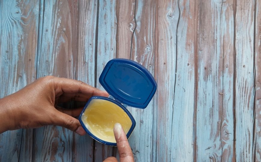 Apply vaseline on your eyelashes A hand on a vaseline pot