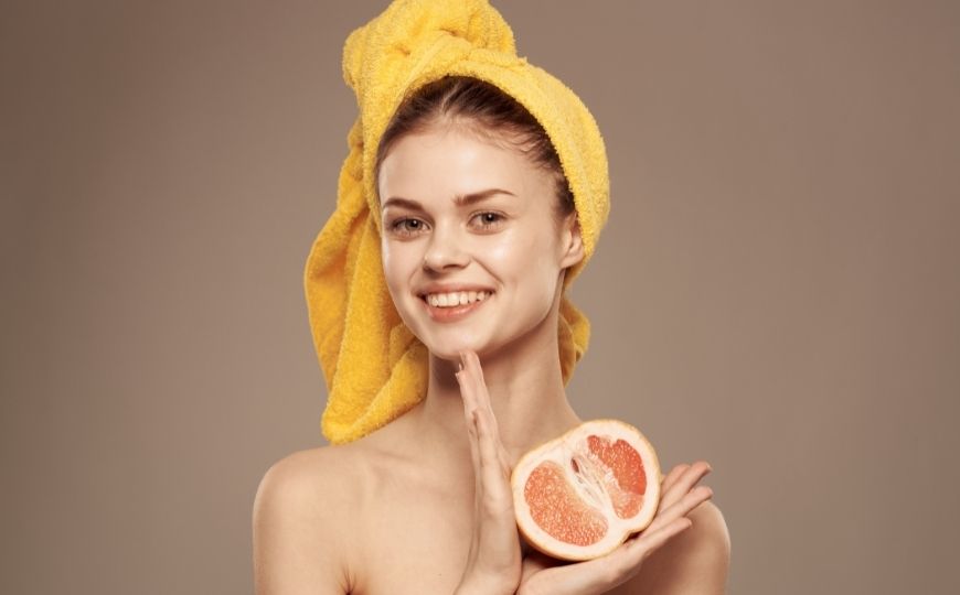 Woman with a towel on her head holding an orange