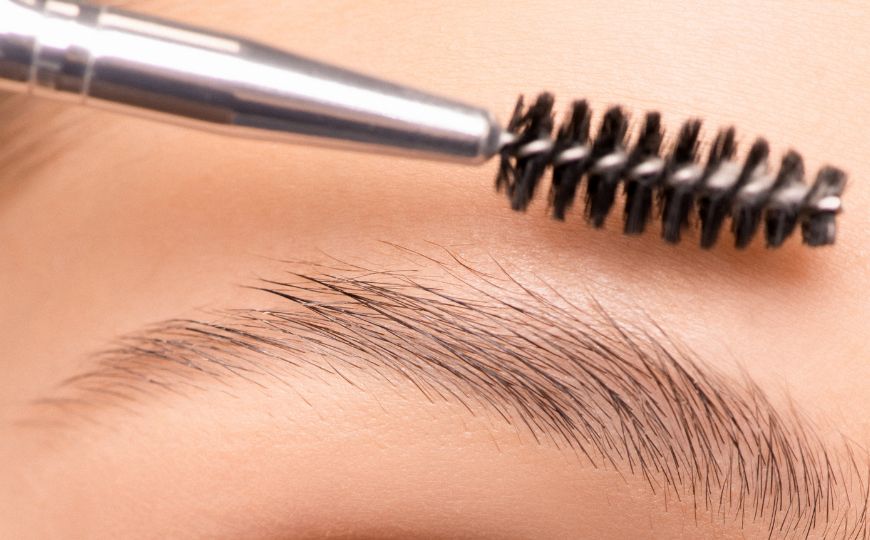 A woman brushing her eyebrows