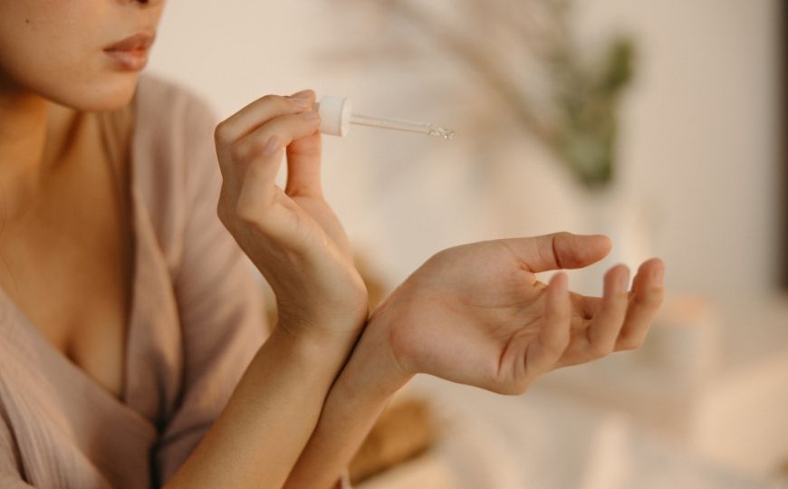 Woman applying scented oil on her wrists